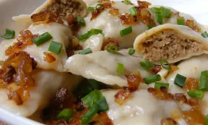 Pyszne pierogi z mięsem, okraszone skwarkami i szczypiorkiem, kuszą swoim domowym wyglądem.