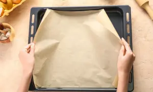 Ręce układają papier do pieczenia na blasze. Zastanawiasz się, czym zastąpić papier do pieczenia? Masz już składniki do ciasta.