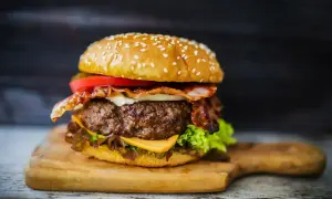 Soczysty burger z wołowiny, idealne mięso na burgery, z bekonem, serem i warzywami na desce.