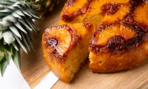 Pyszne, karmelizowane ciasto z patelni z kawałkami ananasa, obok świeży ananas.