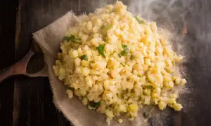 Gorąca kasza bulgur gotowanie na drewnianym stole, parująca i ozdobiona zielonymi ziołami.