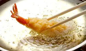Krewetka w chrupiącej panierce panko smaży się w gorącym oleju.