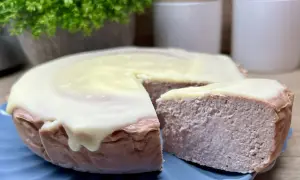 Pyszny sernik z białą czekoladą, z kawałkiem odciętym na niebieskim talerzyku.