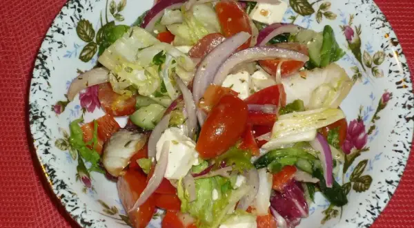 Pyszna sałatka z mix sałat, pomidorów, ogórka, czerwonej cebuli i sera feta, polana ziołowym dressingiem.