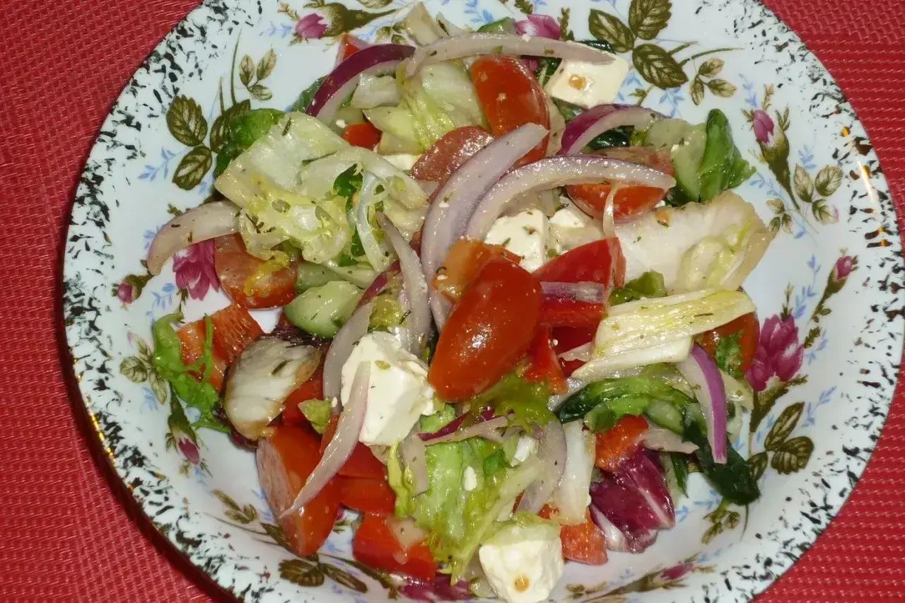 Pyszna sałatka z mix sałat, pomidorów, ogórka, czerwonej cebuli i sera feta, polana ziołowym dressingiem.