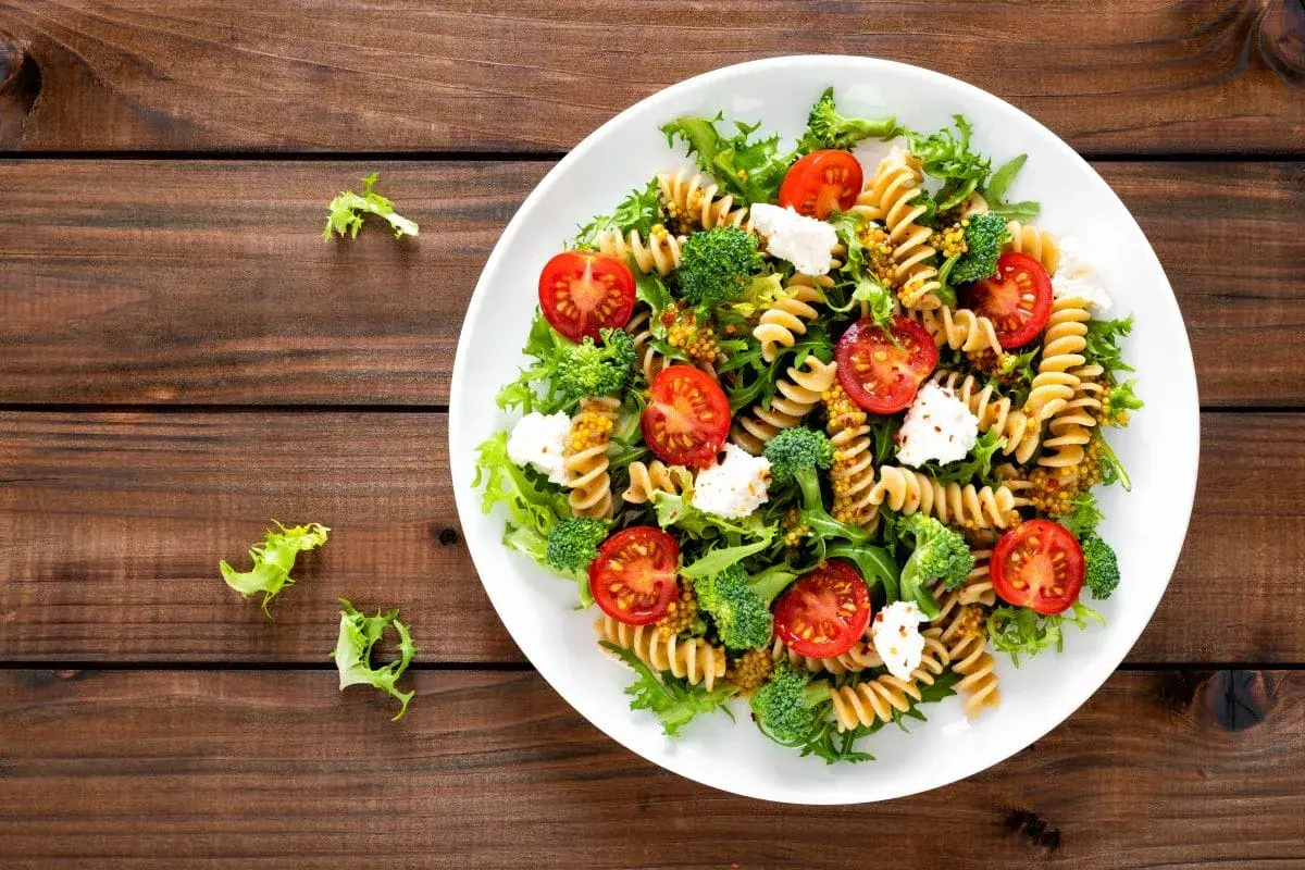 Kolorowa sałatka z makaronem fusilli, pomidorkami koktajlowymi, brokułami i fetą, polana musztardowym dressingiem. Pyszne danie na lekki obiad.