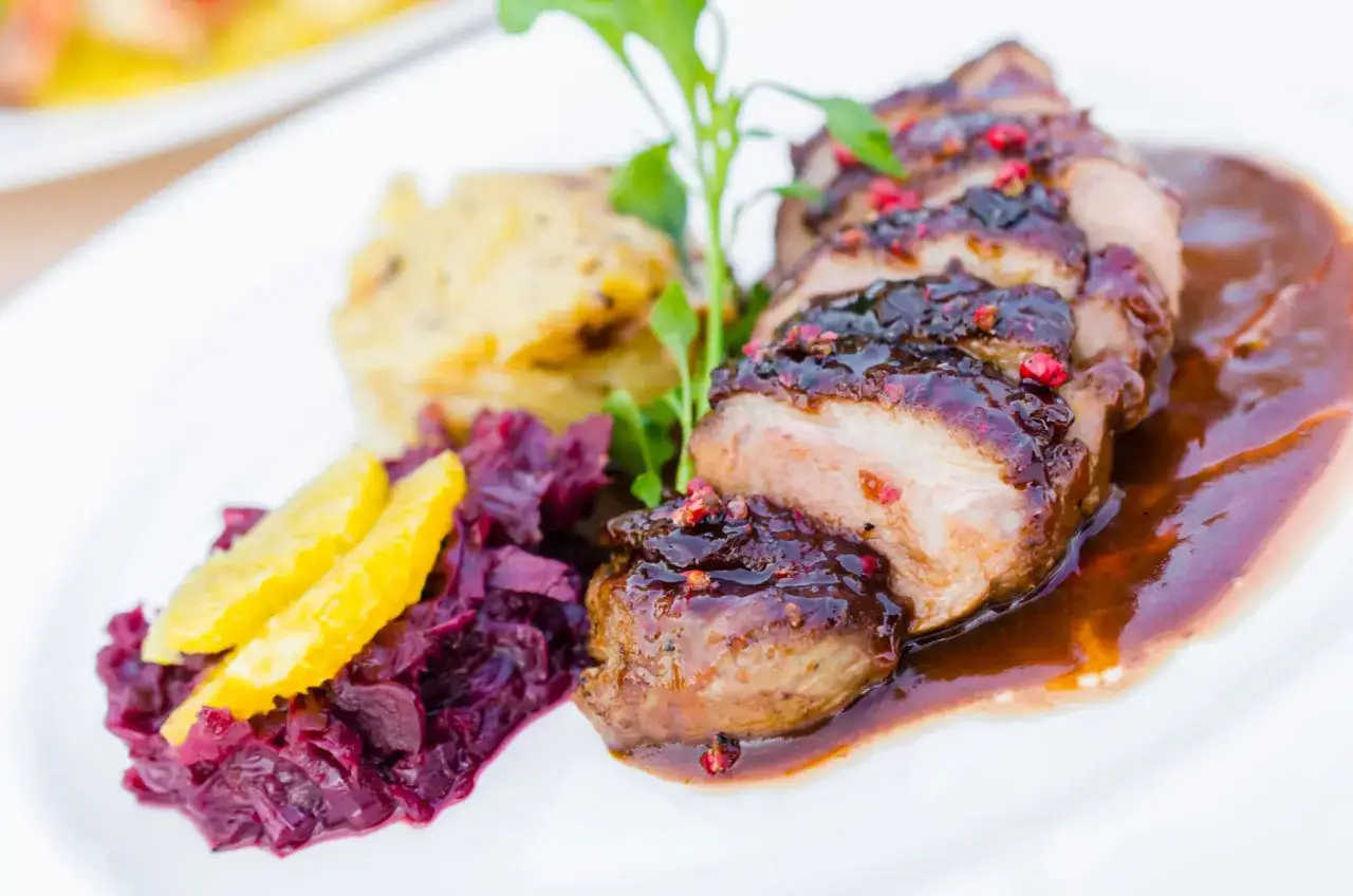 Soczysta pierś z kaczki w sosie, podana z pur&eacute;e ziemniaczanym i czerwoną kapustą z pomarańczą.