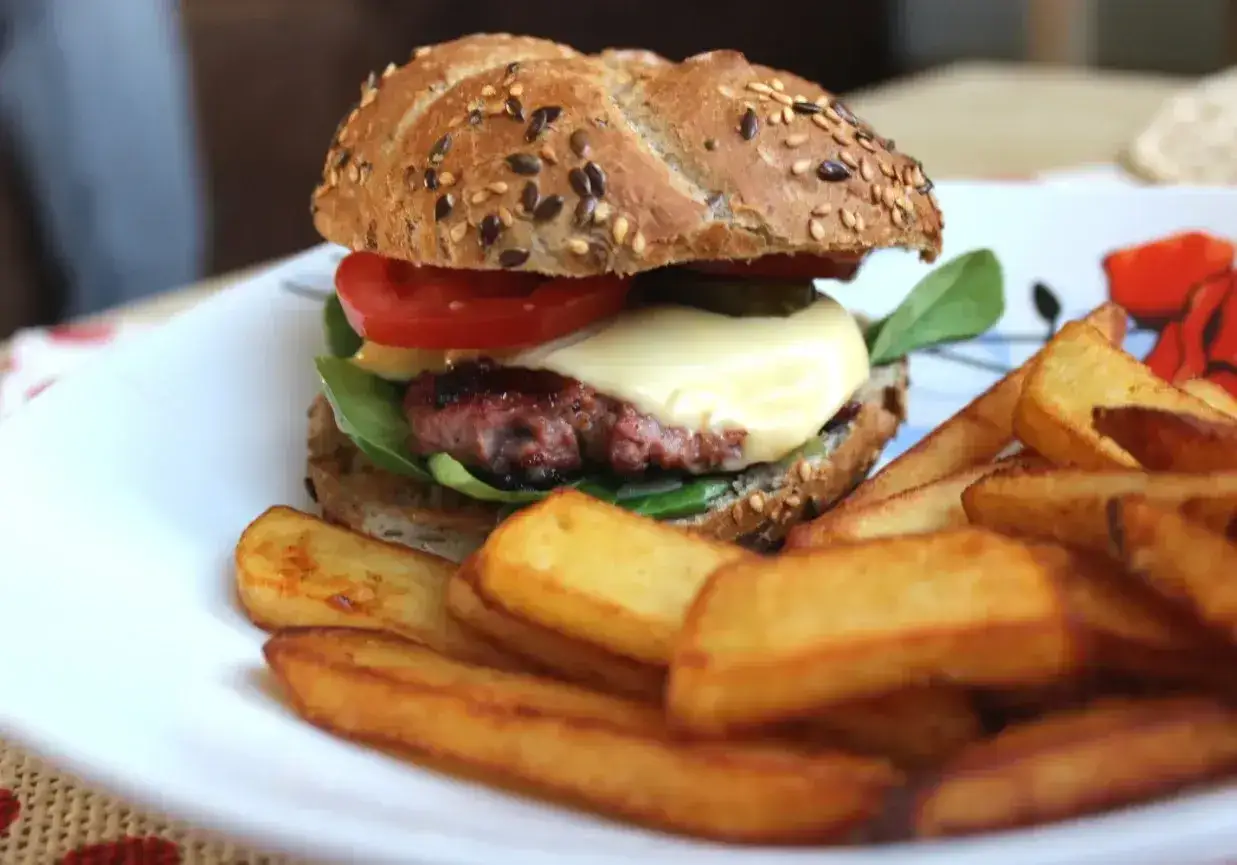 Soczysty burger z wołowiny, idealne jakie mięso na burgery, z serem, pomidorem i frytkami.