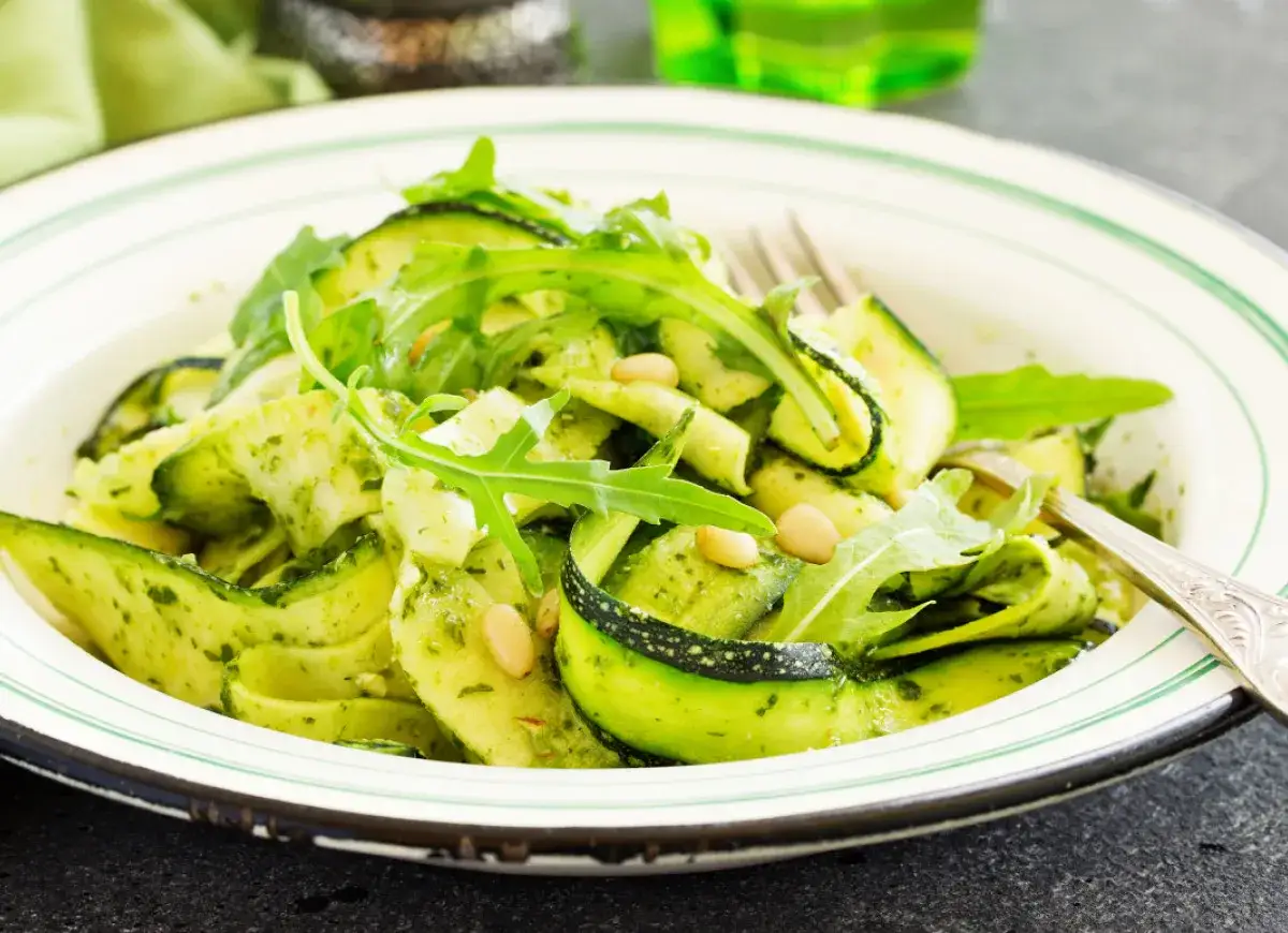 Sałatka z cukinii w sosie pesto, z rukolą i orzeszkami pinii. Czy cukinię się obiera? W tej potrawie nie, sk&oacute;rka dodaje koloru i tekstury.