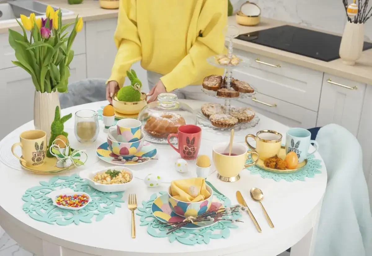 St&oacute;ł zastawiony na Wielkanoc: kolorowe filiżanki, babka, ciastka, pisanki i zajączki tworzą efektowne dania wielkanocne.
