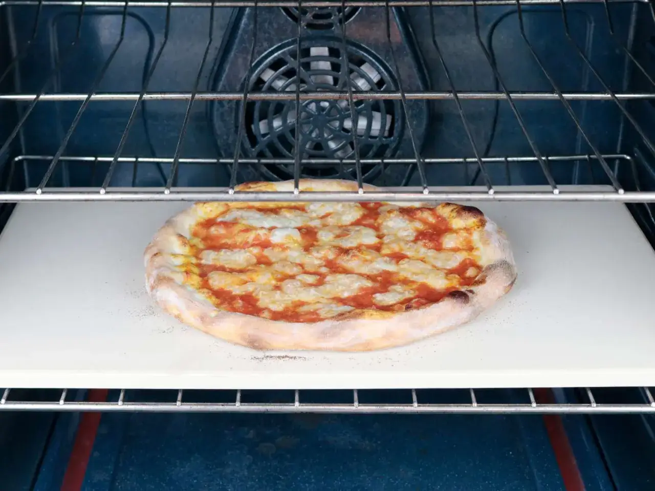 Margherita pizza pieczona na kamieniu w piekarniku. Idealna temperatura do pieczenia pizzy to klucz do chrupiącego ciasta i rozpływającego się sera.