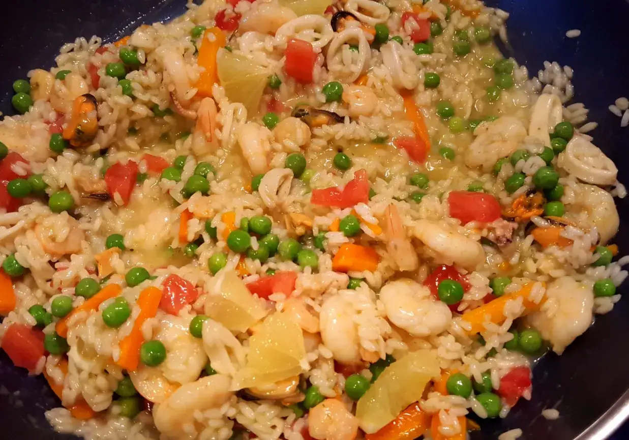 Pyszne risotto z owocami morza, krewetkami, małżami, kalmarami, groszkiem i pomidorami.