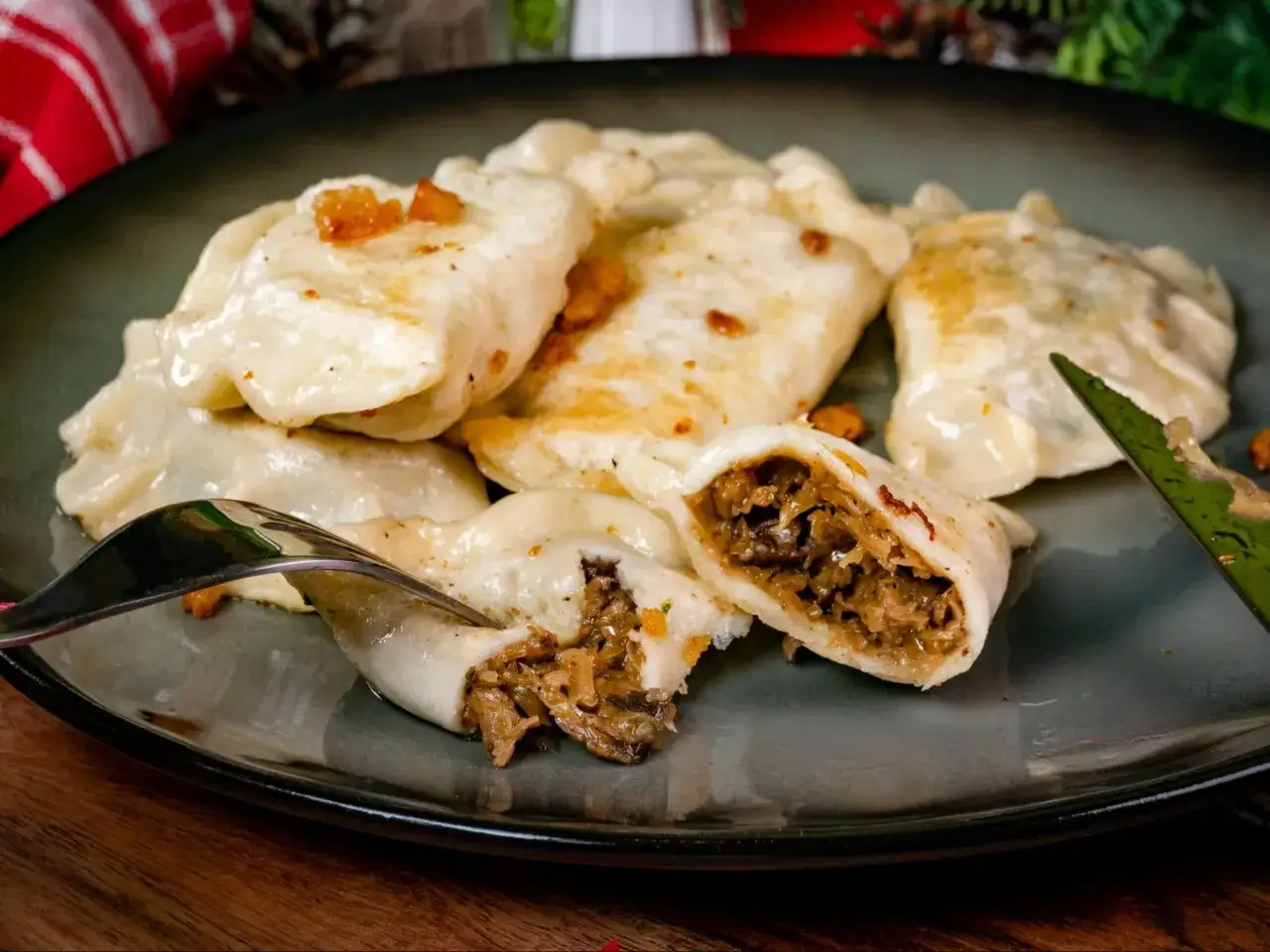 Pyszne pierogi z kapustą i grzybami, jeden przekrojony widelcem, odsłaniający bogate nadzienie.