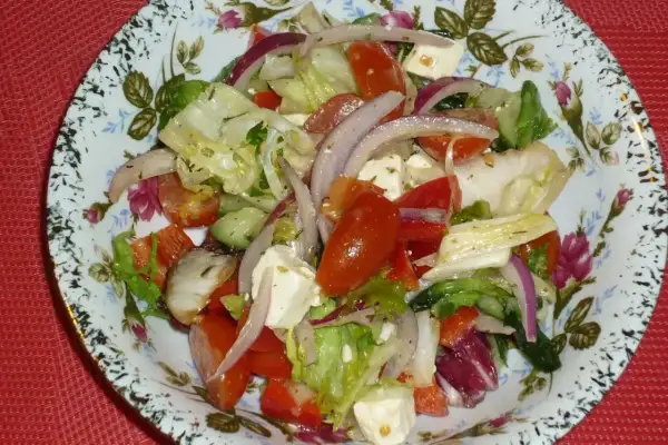 Pyszna sałatka z mix sałat, pomidorów, ogórka, czerwonej cebuli i sera feta, polana ziołowym dressingiem.